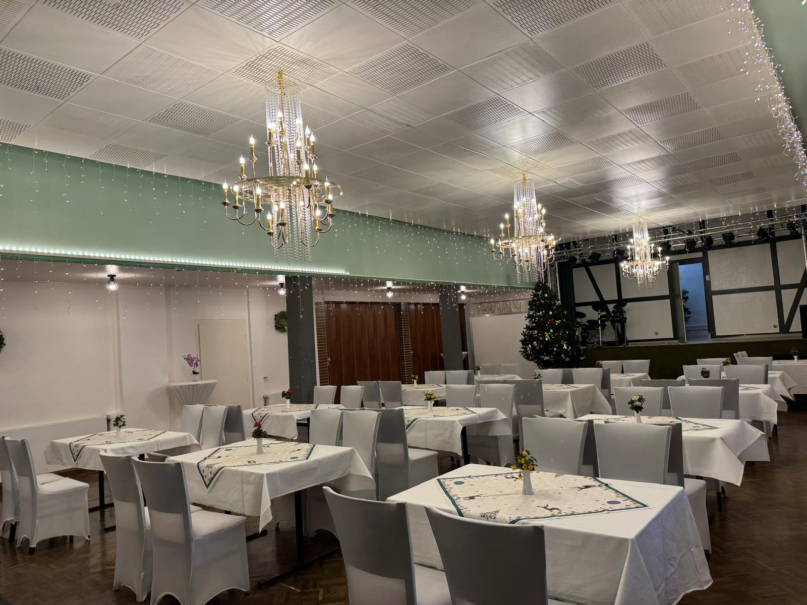 Festlich eingedeckter Saal mit Kronleuchtern und Bühne